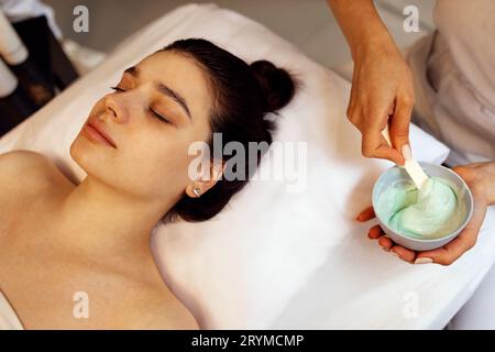 Esthéticienne appliquant le masque d'alginate sur le visage de la femme avec une peau douce et lisse Banque D'Images