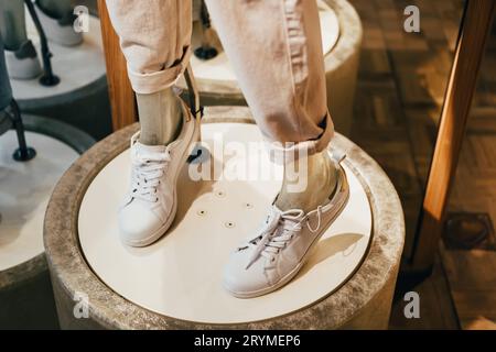 Jambes de mannequin en cuir blanc baskets sur Catwalk dans le magasin de chaussures, mise au point sélective Banque D'Images