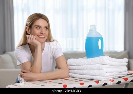 Femme avec assouplissant et serviettes propres dans la chambre Banque D'Images