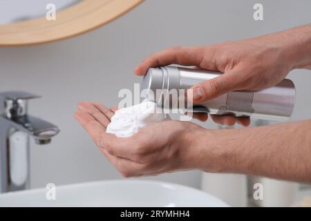 Homme appliquant de la mousse à raser sur la main dans la salle de bain, gros plan Banque D'Images