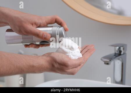 Homme appliquant de la mousse à raser sur la main dans la salle de bain, gros plan Banque D'Images