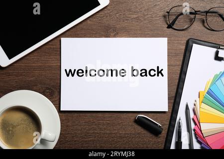 Papier avec phrase Welcome Back sur la table en bois. Bureau avec tablette et café, plat Banque D'Images