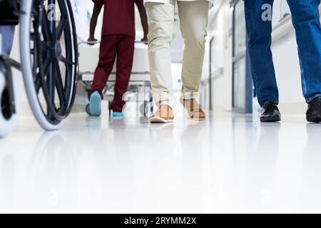 Petit nombre de médecins masculins et fauteuil roulant dans un couloir hospitalier très fréquenté, espace de copie Banque D'Images