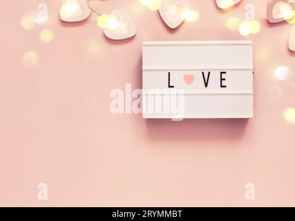 Décoration pastel de Saint-Valentin avec mot amour sur un tableau lumineux et guirlande en forme de coeur. Concept de fête de Saint-Valentin ou de mariage Banque D'Images