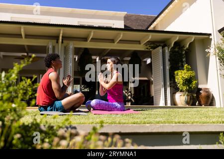 Joyeux couple de forme diverse pratiquant la méditation de yoga assis dans le jardin ensoleillé, avec l'espace de copie Banque D'Images