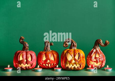 Halloween diy citrouilles en céramique Jack lanterne et bougies sur fond vert pin, espace de copie Banque D'Images