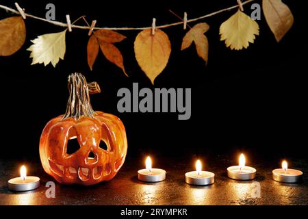 Lanterne de citrouille en céramique d'Halloween et bougies sur fond noir. Carte de vœux Banque D'Images