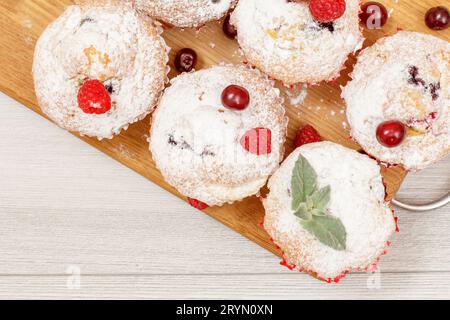 Muffins aux fruits maison saupoudrés de sucre en poudre et de framboises fraîches Banque D'Images