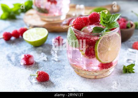 Cocktail seltzer dur avec framboises et citron vert sur un plateau en pierre grise. Banque D'Images