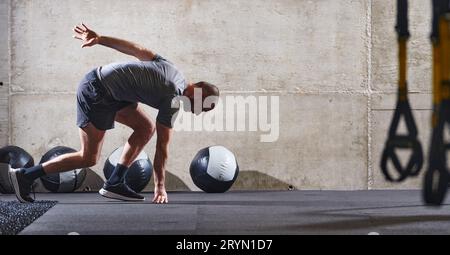 Un homme musclé capturé dans l'air alors qu'il saute dans une salle de gym moderne, mettant en valeur son athlétisme, sa puissance et sa détermination à travers un highi Banque D'Images