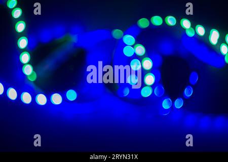 Boucles floues au néon vert et bleu de lumières LED bokeh sur noir. Arrière-plan abstrait Banque D'Images
