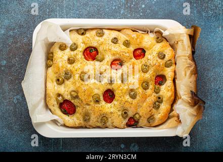 Au-dessus du pain traditionnel italien maison Focaccia avec olives vertes, huile d'olive, tomates cerises et romarin en Bakin Banque D'Images