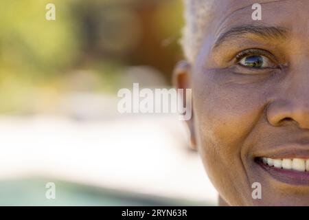 Demi portrait de la femme biraciale aînée heureuse souriant dans le jardin ensoleillé, espace copie Banque D'Images