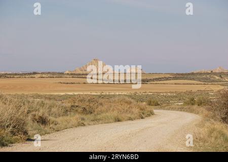 Route de gravier à travers le paysage désertique du plateau aride des Bardenas Reales menant à la formation rocheuse bizarre, Arguedas, Navarre, Espagne Banque D'Images