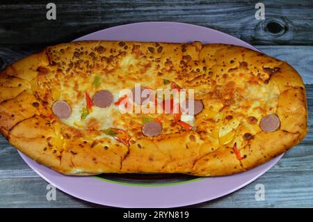 Fromage Fougasse recouvert de tranches de poivrons verts, de fromage et de saucisses coupées cuites au four, le pain de fougasse est un type de pain typiquement associé Banque D'Images