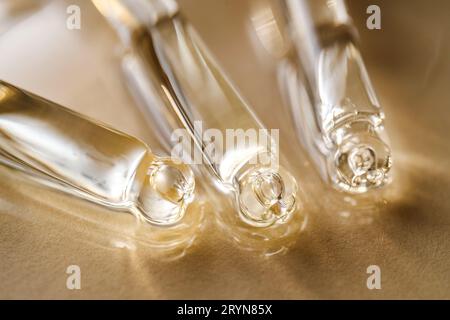 Pipettes avec huile ou sérum sur fond doré. Banque D'Images