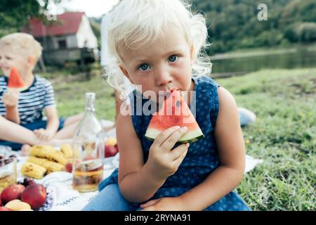 En gros plan, une petite fille mange de la pastèque à l'extérieur. Banque D'Images