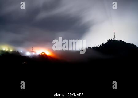 Prise de vue nocturne longue montrant le brouillard et les nuages roulant sur les montagnes avec des lumières bleues et oranges du village de Darjeeling, Shimla, manali Banque D'Images