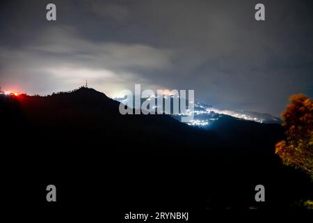 Photo de nuit montrant le village de darjeeling niché au milieu des montagnes de l'himalaya avec une lumière orange et bleue Banque D'Images
