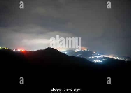 Photo de nuit montrant le village de darjeeling niché au milieu des montagnes de l'himalaya avec une lumière orange et bleue Banque D'Images