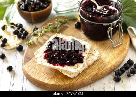 Confiture de cassis dans un pot en verre et pain croustillant sans gluten sur une table rustique. Banque D'Images