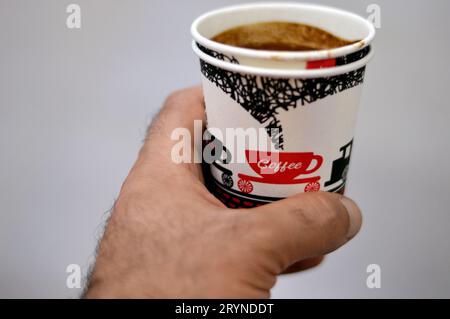 Une tasse de café turc bu dans une tasse de mousse jetable dans une main humaine, avec le texte du café, la tasse et une figure de train, les tasses de mousse sont isolées Banque D'Images