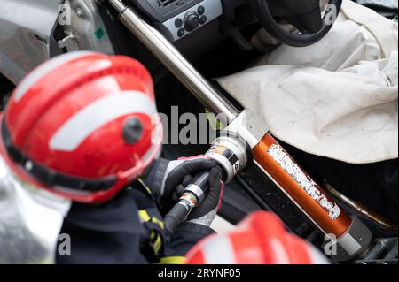 Pompiers utilisant des outils hydrauliques lors d'une formation aux opérations de sauvetage. Les sauveteurs déverrouillent le passager dans la voiture après un accident. Banque D'Images