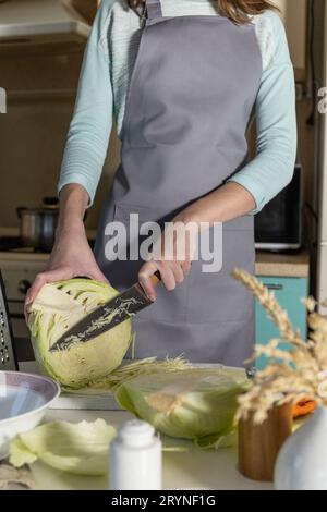 Mise en conserve de choucroute.Une jeune femme prépare de la choucroute maison avec des carottes dans la cuisine.Aliments fermentés. Banque D'Images