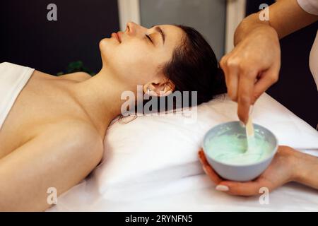 Esthéticienne appliquant le masque d'alginate sur le visage de la femme avec une peau douce et lisse Banque D'Images