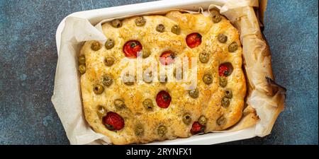 Au-dessus du pain traditionnel italien maison Focaccia avec olives vertes, huile d'olive, tomates cerises et romarin en Bakin Banque D'Images