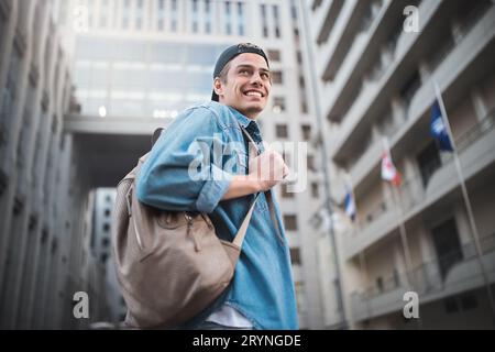 Jeune homme gai avec sac à dos en train de marcher la ville Banque D'Images