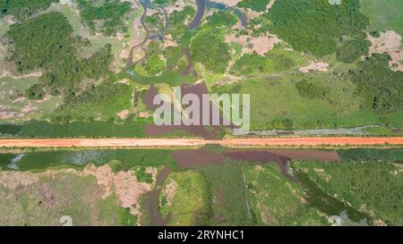 Vue aérienne de Transpantaneira traversée de route de terre dans le paysage typique des zones humides du Pantanal avec lagune Banque D'Images