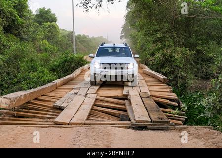 SUV blanc traversant un pont en bois délabré sur la route de Transpantaneira à travers le Pantanal Nord o Banque D'Images