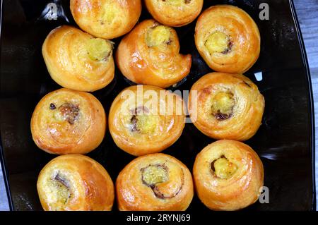 Mini rouleau de bouffée tourbillon à la cannelle sucré avec du miel et des raisins secs et rempli de crème anglaise cuit au four, sélection de pâtisseries croissants boulangerie rolle Banque D'Images