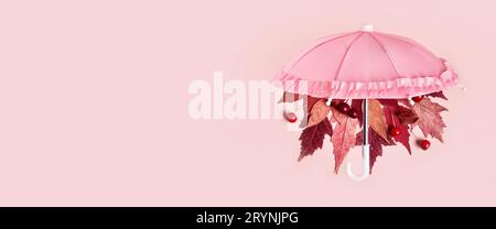 Les feuilles d'automne tombent du parapluie rose sur la bannière pastel rose. Concept créatif Hello Autumn Banque D'Images