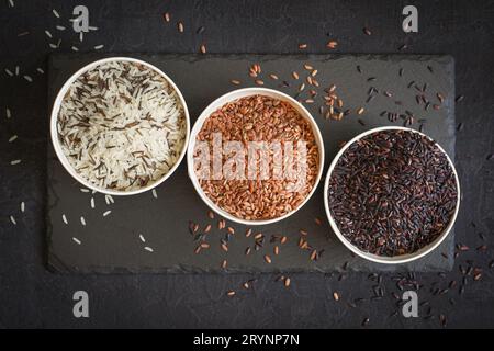 Assortiment de variété de riz gastronomique dans des bols sur fond noir. Vue de dessus Banque D'Images