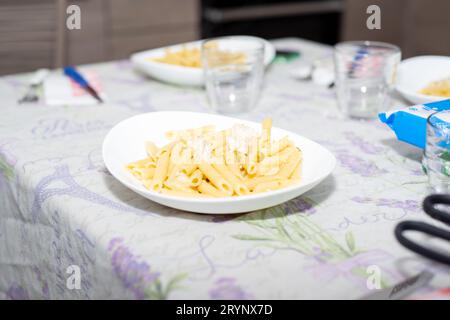 penne, pâtes italiennes avec poulet et pois sur une assiette sur une table posée Banque D'Images
