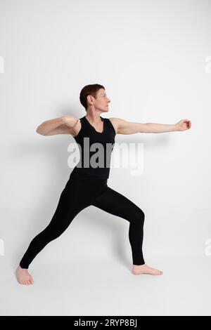 Femme mature athlétique vêtue de noir, imitant le geste sportif du tir à l'arc Banque D'Images