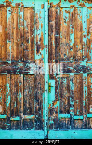 Vieille porte de portail en bois avec peinture bleue qui se décolle, porte usée avec poignée métallique Banque D'Images