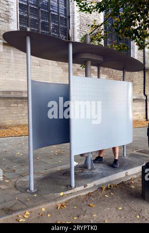Homme utilisant un urinoir public gratuit dans le centre de Bruxelles, Belgique. Il est illégal d’uriner dans un espace public à Bruxelles. Banque D'Images