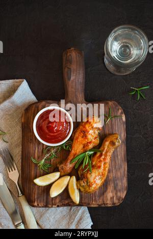 Le pilon de poulet épicé grillé est servi sur une planche de bois. Haut Banque D'Images