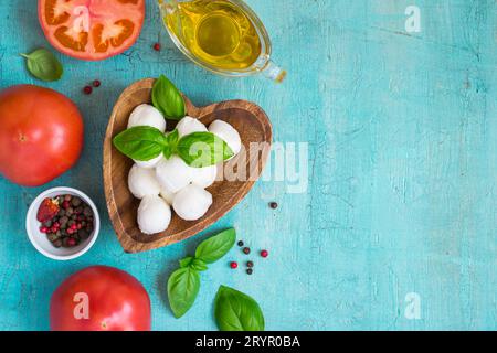 Fromage mozzarella, tomates et basilic sur une table turquoise. Conc Banque D'Images