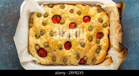 Au-dessus du pain traditionnel italien maison Focaccia avec olives vertes, huile d'olive, tomates cerises et romarin en Bakin Banque D'Images