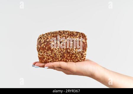 Pain multigrain maison dans la main de femme sur fond blanc Banque D'Images