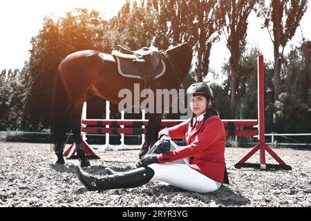 Jeune cavalier sérieux fille et son cheval posant après l'entraînement. Elle aime les animaux et passe joyeusement son temps dans leur environnement Banque D'Images