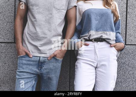 Photo Un jeune couple moderne d'adolescents en arrière-plan du mur. Photo sans visages. Vue rapprochée Banque D'Images