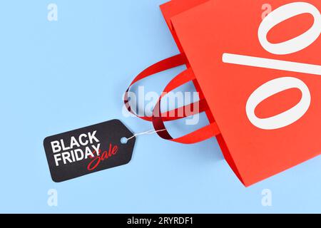 Sac à provisions rouge avec étiquette avec étiquette de vente Black Friday sur fond bleu Banque D'Images