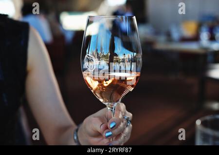 Gastronomie à Sydney avec un verre de vin rosé tenu par une femme dans une main, déjeuner au restaurant Bennelong de l'Opéra de Sydney Banque D'Images