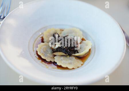 Chouette de cochon fumé, salami et raviolis aux champignons à la truffe, servis dans une assiette blanche profonde, Blate - cuisine fine au Bennelong Restaurant, Sydney, Australie Banque D'Images