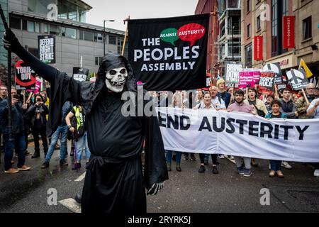 Un homme habillé en squelette mène la marche. Pendant la conférence du Parti conservateur, les gens ont défilé à travers la ville pour une manifestation nationale. Organisées par l'Assemblée des peuples et rejointes par les syndicats, les revendications incluent la fin de la crise du coût de la vie et la défense du NHS. Banque D'Images